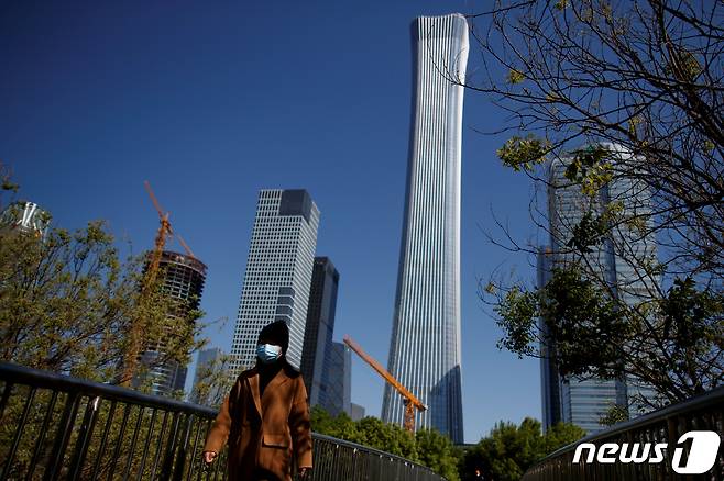 지난달 22일 중국 베이징에서 마스크를 쓴 한 여성이 걸어가고 있다.© 로이터=뉴스1