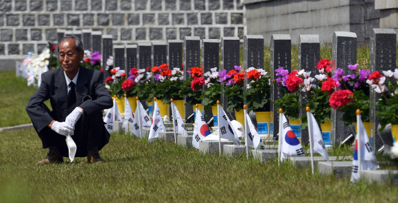 잊을 수 없는 그날의 아픔 - 5·18 민주화운동 40주년을 하루 앞둔 17일 광주 북구 국립 5·18민주묘지에서 희생자의 묘비를 찾은 유족이 마스크를 벗은 채 쪼그려 앉아 생각에 잠겨 있다.박지환 기자 popocar@seoul.co.kr