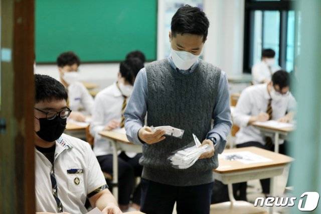 (광주=뉴스1) 신종 코로나바이러스 감염증(코로나19) 여파로 등교가 5차례나 연기되며 80일 만에 등교 수업이 시작된 20일 오전 광주고등학교 고3 교실에서 교사가 학생들에게 마스크를 나눠주고 있다.2020.5.20/뉴스1