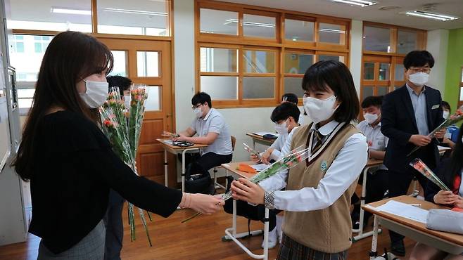 세종 도담고의 한 교사가 20일 첫 등교한 고3 수험생들에게 미니장미꽃을 주며 격려하고 있다. 도담고 제공