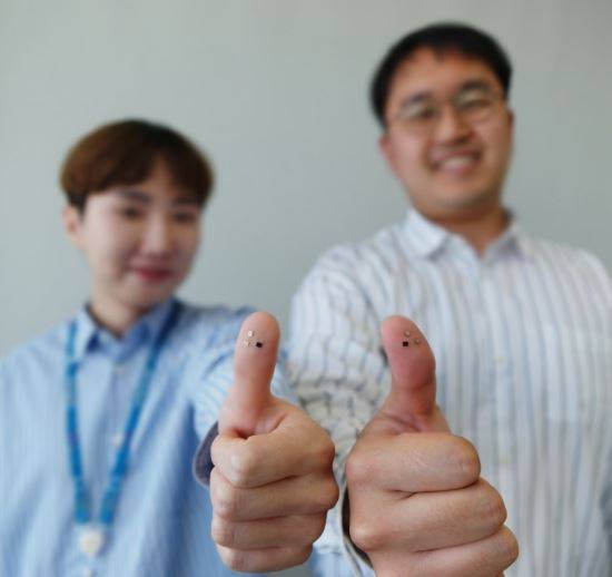 두 사람이 삼성전자 차세대 핵심 보안칩 'S3FV9RR'을 손톱 위에 붙인 엄지를 들어 보이고 있다. 삼성전자 제공
