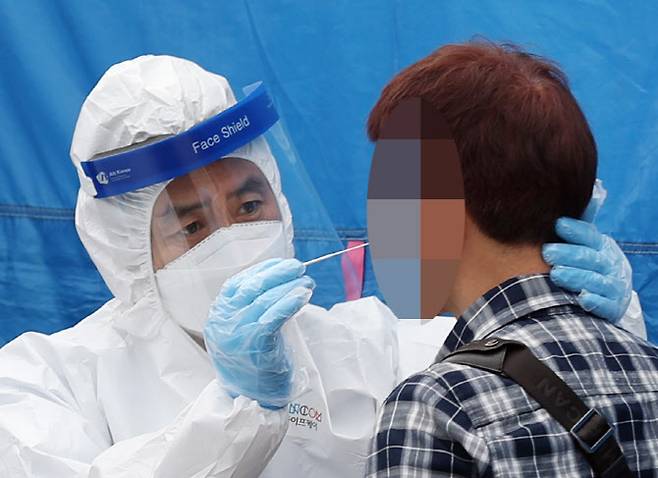 경기도 부천 쿠팡 물류센터에서 신종 코로나바이러스 감염증(코로나19) 확진자가 속출한 27일 오전 경기도 부천시 종합운동장 외부 주차장에 마련된 선별진료소에서 보건 당국 관계자가 한 시민을 검체 검사하고 있다 (사진=연합뉴스)