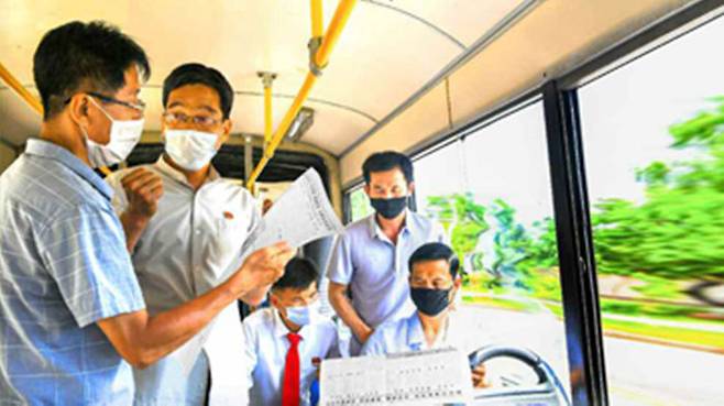 평양 거리를 달리는 무궤도전차 안에서 마스크를 쓴 주민들이 노동신문을 읽으며 분노하고 있는 모습