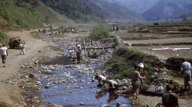 1951년 3월 초 어느 산간마을에서 공사하는 군인들 사이로 지나가는 피란민 행렬