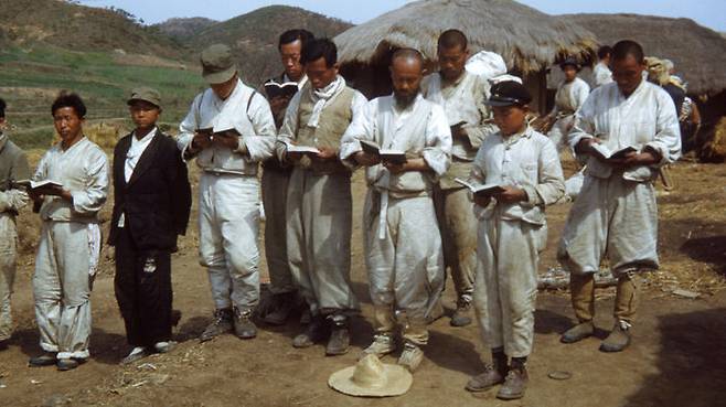1951년 피란길 도중 마을 집 앞에서 성경책 읽는 사람들