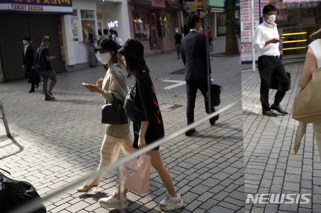 [도쿄=AP/뉴시스]지난 26일 일본 도쿄의 한 상점가의 거울에 마스크를 쓴 채 걸어가는 사람들이 비치고 있다. 2020.06.29.