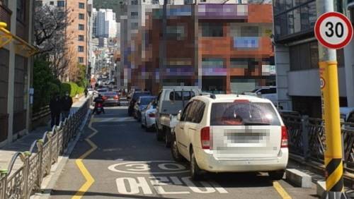 이른바 ‘민식이법’ 시행에도 불법주정차 여전… 학교 앞 어린이 교통안전을 대폭 강화한 ‘민식이법’&nbsp;시행 첫날인 지난 3월25일 부산진구 한 초등학교 앞에 차들이 줄지어 불법 주차돼있는 모습. 연합뉴스