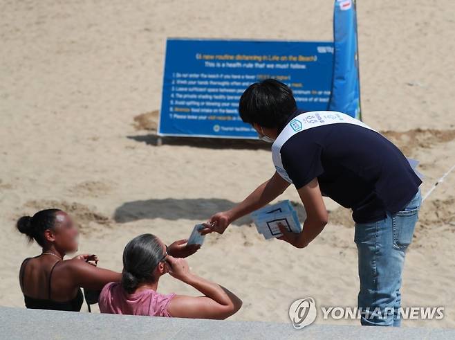 "마스크 착용해 주세요" (부산=연합뉴스) 손형주 기자 = 5일 오후 부산 해운대구 해운대해수욕장에서 부산시와 해운대구 관계자들이 외국인들을 대상으로 코로나19 거리 두기 캠페인을 벌이며 마스크를 나눠주고 있다. 2020.7.5 handbrother@yna.co.kr