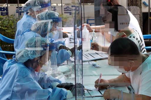 7일 오후 광주 광산구 신창동 행정복지센터에 마련된 코로나19 간이 선별진료소에서 시민이 진단검사 서류를 작성하고 있다. 보건당국은 신창동의 대형사우나 관계자 3명이 잇따라 코로나19 확진 판정을 받자 긴급 역학조사에 나섰다. 연합뉴스