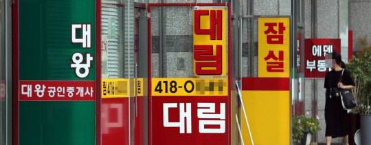 한 시민이 부동산공인중개업소에 걸린 아파트 급매물 시세를 살펴보고 있다.<연합뉴스>