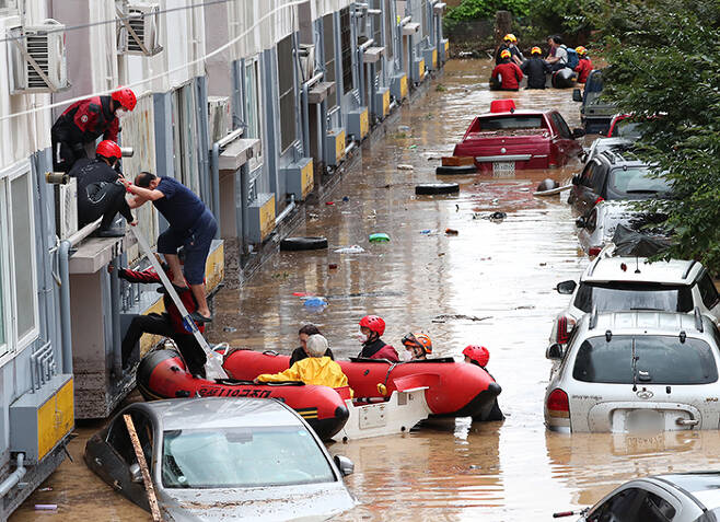30일 대전 서구의 한 아파트에서 집 안에서 구조를 기다리던 주민들이 119구조대의 도움을 받아 고무보트에 타고 있다. 빗물은 구조대원들의 허리 높이까지 차올랐고 아파트에 주차된 차들은 침수됐다. /신현종 기자