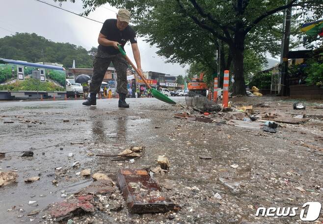화개장터 앞 도로의 유리 등 쓰레기들을 자원봉사자가 청소하고 있다. © 뉴스1