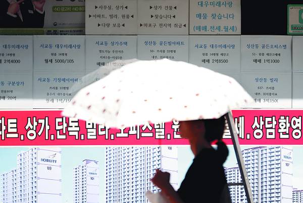 한 행인이 19일 서울 마포구의 한 부동산중개업소 앞을 지나고 있다. 정부가 이날 전월세 전환율을 4.0%에서 2.5%로 낮추는 방안을 밝힌 가운데 시장에서는 강제성이 없는 ‘종이호랑이’ 보완책에 그칠 것이라는 우려가 나오고 있다. 연합뉴스
