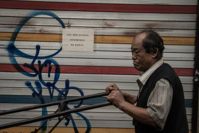 리어카에 자재를 싣고 걸음을 재촉하는 한 상인의 뒤로 '그동안의 성원에 감사합니다, 영업을 종료합니다'라고 쓰인 안내피켓이 굳게 닫힌 셔터 위에 나붙어 있다.