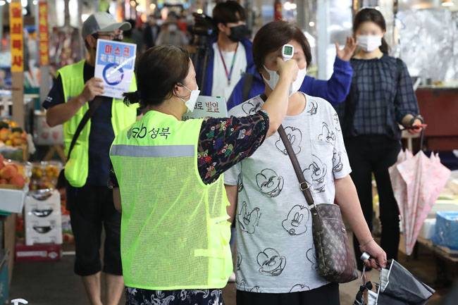 2일 오후 서울 성북구 한 전통시장에서 시장 관계자가 출입 손님 체온을 측정하고 있다.  [뉴스1]