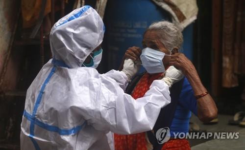 인도 뭄바이의 슬럼가에서 빈민에게 마스크를 씌워주는 의료진(왼쪽). [AP=연합뉴스]