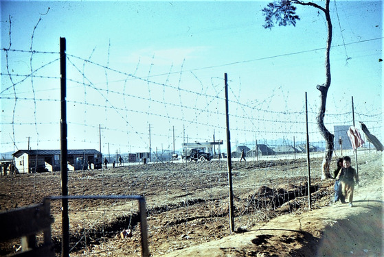 Korean orphans running along the fence of the K-55 air base, where South African forces were stationed, in a photo taken by Sgt. Louw. [SOUTH AFRICAN KOREAN WAR VETERANS ASSOCIATION]