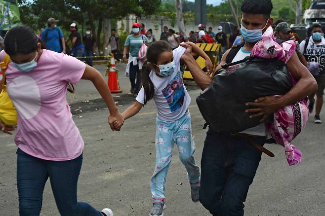 이민자 부부와 딸이 1일(현지시간), 온두라스 코린 토 국경에서 과테말라로 들어가기 위해 필사적으로 경찰 울타리를 통과하고 있다.(Photo by ORLANDO SIERRA / AFP)