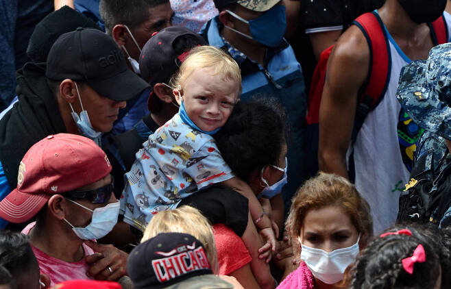 아빠의 어깨에 목마를 탄 온두라스 이민자 어린이가 1일(현지시간) 과테말라 국경으로 향하고 있다. 이날 과테말라로 들어간 이민자들은 3천 명을 넘었다. (Photo by ORLANDO SIERRA / AFP)