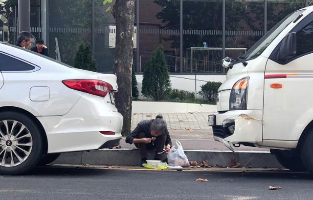 추석 당일이었던 지난 1일 오후 경기 성남시 안나의집 앞 도로변에서 한 노숙인이 안나의집에서 받은 도시락을 먹고 있다. 이승엽 기자