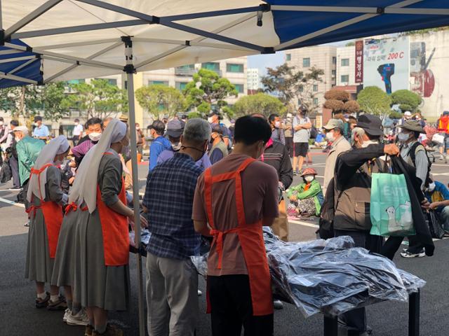 1일 오후 경기 성남시 성남동성당에서 안나의집 자원봉사자들이 노숙인들에게 옷을 나눠주고 있다. 이승엽 기자