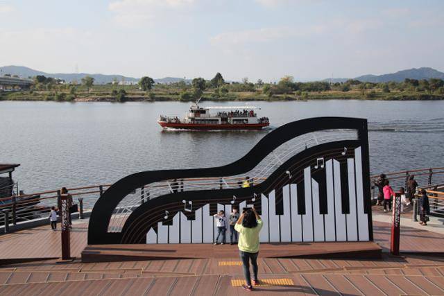 사문진은 1900년 국내 최초로 피아노를 들여온 곳이다. 피아노 조형물 뒤로 유람선이 지나고 있다. ⓒ박준규