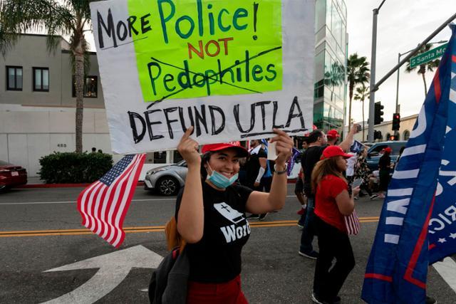 지난달 31일 미국 캘리포니아주 로스앤젤레스 베버리힐스에서 열린 도널드 트럼프 대통령 지지 집회에서 한 여성이 극우 음모론 큐어넌(QAnon)의 팻말을 들고 있다. 베버리힐스=AFP 연합뉴스