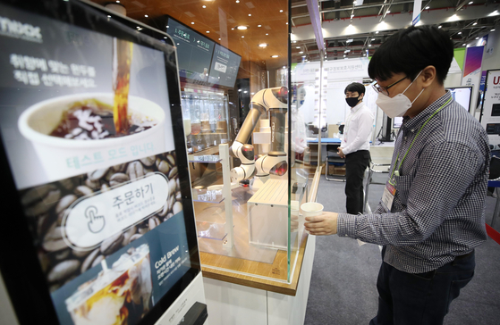 A visitor to the 2020 Korea ICT Convergence Expo tries out the services of an unmanned coffee stand and barista robot at Exco in Buk District, Daegu on Thursday. [YONHAP]