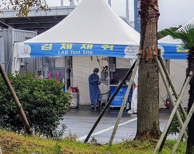 19일 오전 서울과 경기지역을 중심으로 발효됐던 호우 특보가 해제된 가운데 제주 용담이동 제주국제공항 인근의 신종 코로나바이러스 감염증(코로나19) 선별진료소에서 의료진이 검체를 채취하고 있다. 이날 코로나19 신규확진자는 343명 발생했으나 제주도에는 추가확진자가 나오지 않은 상태다./사진=황덕현 뉴스1 기자