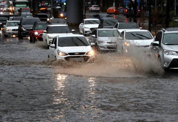 19일 오전 서울 서대문구 경찰청 사거리 인근 도로가 침수돼 차들이 거북이 운행을 하고 있다. 연합뉴스