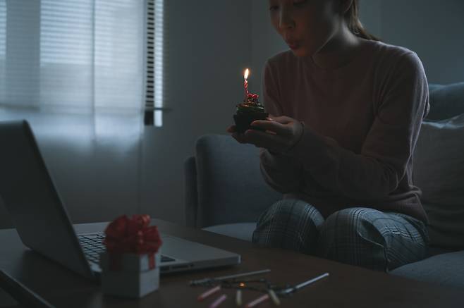 A woman celebrates a friend’s birthday via video call at home. (123rf)