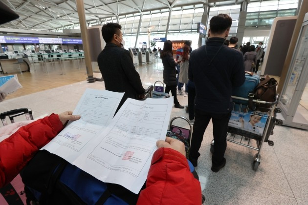 지난 11일 인천국제공항 체크인카운터에서 승객들이 신종 코로나바이러스 감염증(코로나19) 음성확인서를 두 장을 준비하고 있는 모습. 연합뉴스