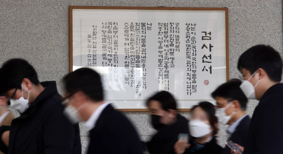 People walk past a framed prosecutors' oath at the Seoul Central District Prosecutors' Office in Seocho District, southern Seoul, Thursday. Prosecutors have been holding meetings to discuss the justice minister’s suspension of Prosecutor General Yoon Seok-youl over alleged ethical and legal breaches, with some issuing statements protesting the action. [YONHAP]