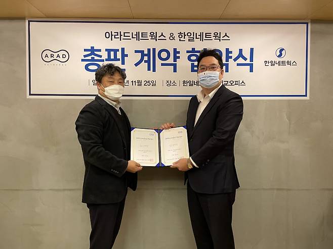 정현우 아라드네트웍스 대표(오른쪽)가 김종원 한일네트웍스 보안사업부문장과 지난 25일 총판 계약 협약서를 교환하고 기념촬영했다.