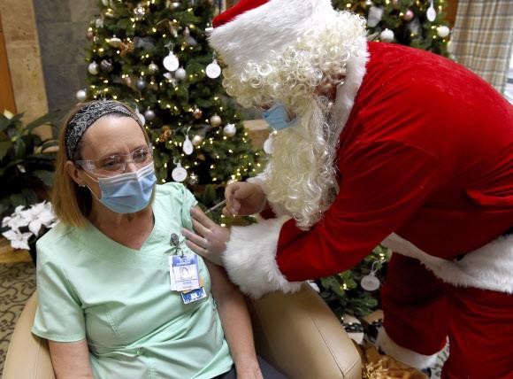 산타 복장을 한 응급전문의가 16일 미국 코넷티컷주 맨체스터 메모리얼병원에서 간호사에게 화이자 백신을 접종하고 있다.맨체스터 로이터 연합뉴스