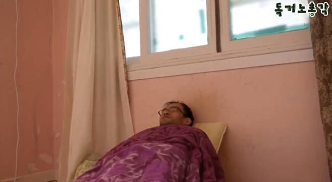 보라색 이불을 덮고 핑크색 벽지에 기대 누워있는 독거노총각 [독거노총각 유튜브 채널]