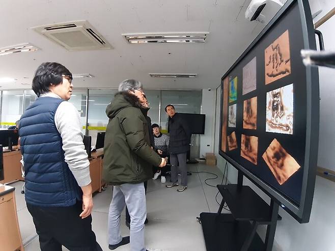 지난달 18일 한국 기술교육대에서 열린 무술오작비 디지털 판독회의 모습. 참석한 학자들이 연단에 몰려나와 대형 모니터에 뜬 비석 명문 글자의 다양한 디지털 이미지를 뜯어보고 있다.