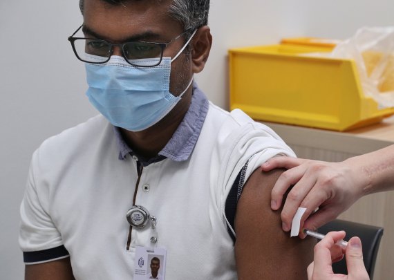 30일 싱가포르에서 현지 의료진이 미국 화이자와 독일 바이오엔테크가 개발한 코로나19 백신을 접종받고 있다.로이터뉴스1