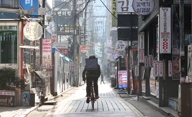 A man riding a bicycle for food delivery passes through restaurants near Gangnam Station, Seoul, Dec. 24. (Yonhap)
