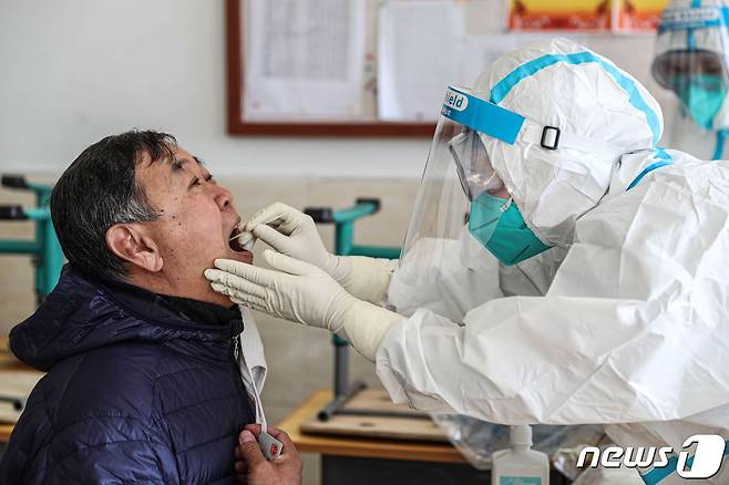 중국 의료진이 한 남성에게 코로나19 검사를 하고 있다. © AFP=뉴스1