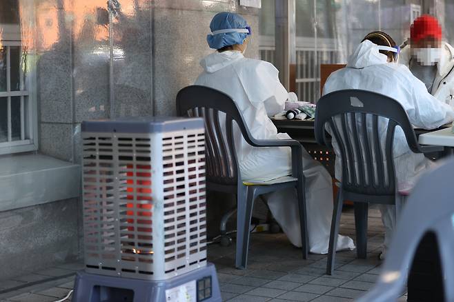 서울 동대문구 보건소에 마련된 선별진료소에서 의료진이 난로에 몸을 녹이며 일하고 있다. [연합뉴스]