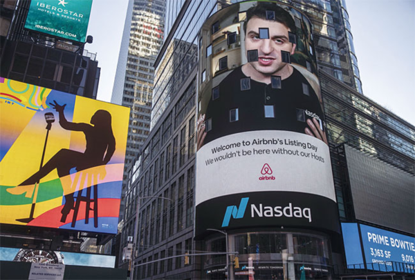 2020년 12월 10일(현지시각) 미국 뉴욕 타임스스퀘어에 있는 나스닥 마켓사이트 빌딩 외벽 스크린에 숙박 공유 업체 에어비앤비의 브라이언 체스키 최고경영자(CEO)의 얼굴이 비치고 있다. / 블룸버그