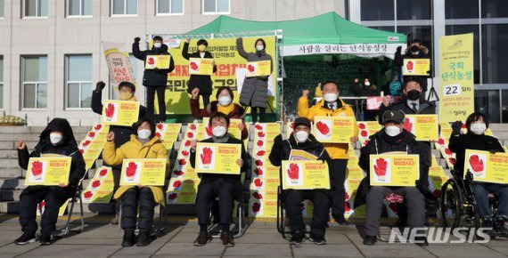 지난 1일 오전 서울 여의도 국회 본관 앞 단식농성장에서 열린 정의당 신년인사회에서 김종철 대표 등 참석자들이 중대재해기업처벌법 제정 촉구 구호를 외치고 있다. 뉴시스화상