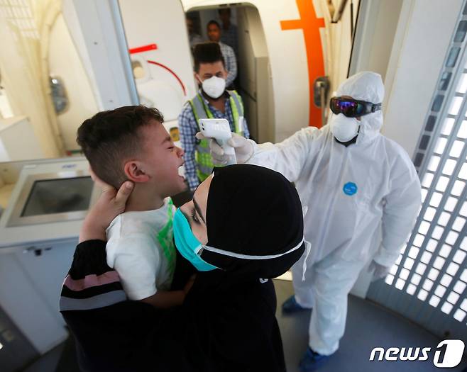 이라크 바스라 공항에서 의료 관계자가 입국하는 어린이의 체온을 측정하고 있다. © 로이터=뉴스1 © News1 포토공용 기자