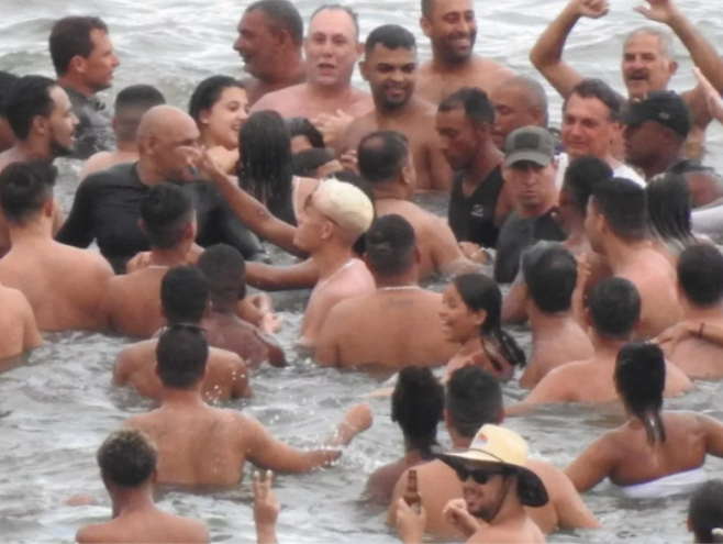 자이르 보우소나루 대통령(오른쪽 상단 흰 옷을 입고 있는 남성)이 지난 1일(현지시간) 상파울루주 프라이아 그란지 해변에서 시민들과 뒤엉켜 물놀이를 하고 있다. SNS 캡처.