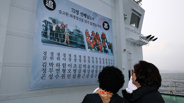 2019년 3월 사고 해상에서 열린 탐색 설명회와 헌화 행사에 참석한 유가족들이 순직자의 명단이 적힌 펼침막을 살펴보고 있다. 연합뉴스
