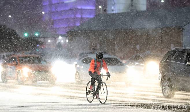 [서울=뉴시스]이영환 기자 = 연일 한파가 이어지며 눈이 내리고 있는 6일 오후 서울 종로구 광화문네거리에서 한 시민이 자전거를 타고 이동하고 있다. 2021.01.06. 20hwan@newsis.com