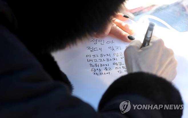 '절대 잊지 않을게' (양평=연합뉴스) 류영석 기자 = 6일 오전 경기 양평 하이패밀리 안데르센 공원묘지를 찾은 한 추모객이 양부모의 학대로 생후 16개월 만에 사망한 피해 아동을 추모하며 편지를 쓰고 있다. 2021.1.6 ondol@yna.co.kr
