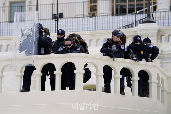 6일(현지시각) 미 국회의사당을 지키기 위해 배치된 경찰이 총을 쥐고 있는 모습 ⓒAP/뉴시스