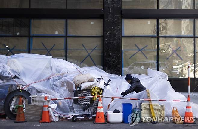 미국 뉴욕의 문닫은 상점 앞에서 물건을 챙기는 한 여성 [EPA=연합뉴스]